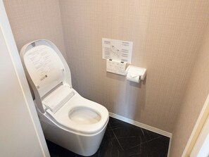 Ein modernes Badezimmer mit Toilette, Papierhandtuchspender und einer an der Wand befestigten Gebrauchsanweisung.