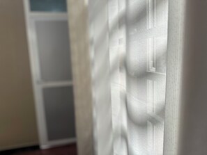 A close-up of a white curtain with a textured pattern.