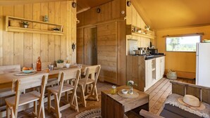 A wooden cabin interior with a dining area, kitchen, and seating space. - Lodge Safari 5p 2bdrms (Muides-sur-Loire)