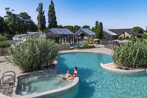 A swimming pool with a hot tub, surrounded by glass structures and greenery. - Lodge Safari 5p 2bdrms (Muides-sur-Loire)