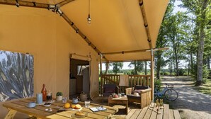 A wooden deck with picnic tables and chairs, a bicycle, and a tent. - Lodge Safari 5p 2bdrms (Muides-sur-Loire)