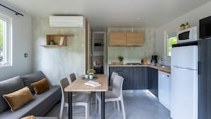 A modern kitchen with grey cabinets, a dining table with chairs, and a built-in oven. - Cottage Dourbie 4p 2bdrms Aircon (Millau)