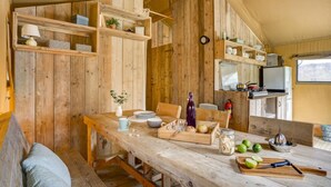 Ein rustikales Holzinterieur mit einem gedecktem Esstisch, einer Küchenzeile mit Geräten und Regalen voller Gegenstände.