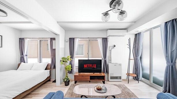 A modern hotel room with a bed, a sofa, a coffee table, a TV, and a large window. - VOLPE 102 (Sapporo)