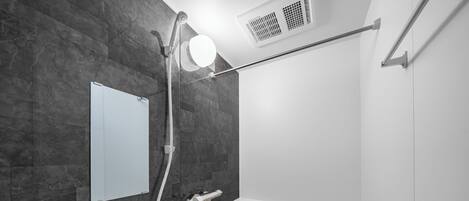 A modern bathroom with a freestanding bathtub, a wall-mounted mirror, and a showerhead.