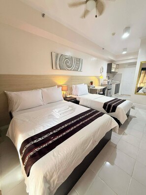 A hotel room with two beds, a small kitchenette, and a ceiling fan. - Cozy Studio Condo With Stunning Tagaytay Views (Tagaytay)