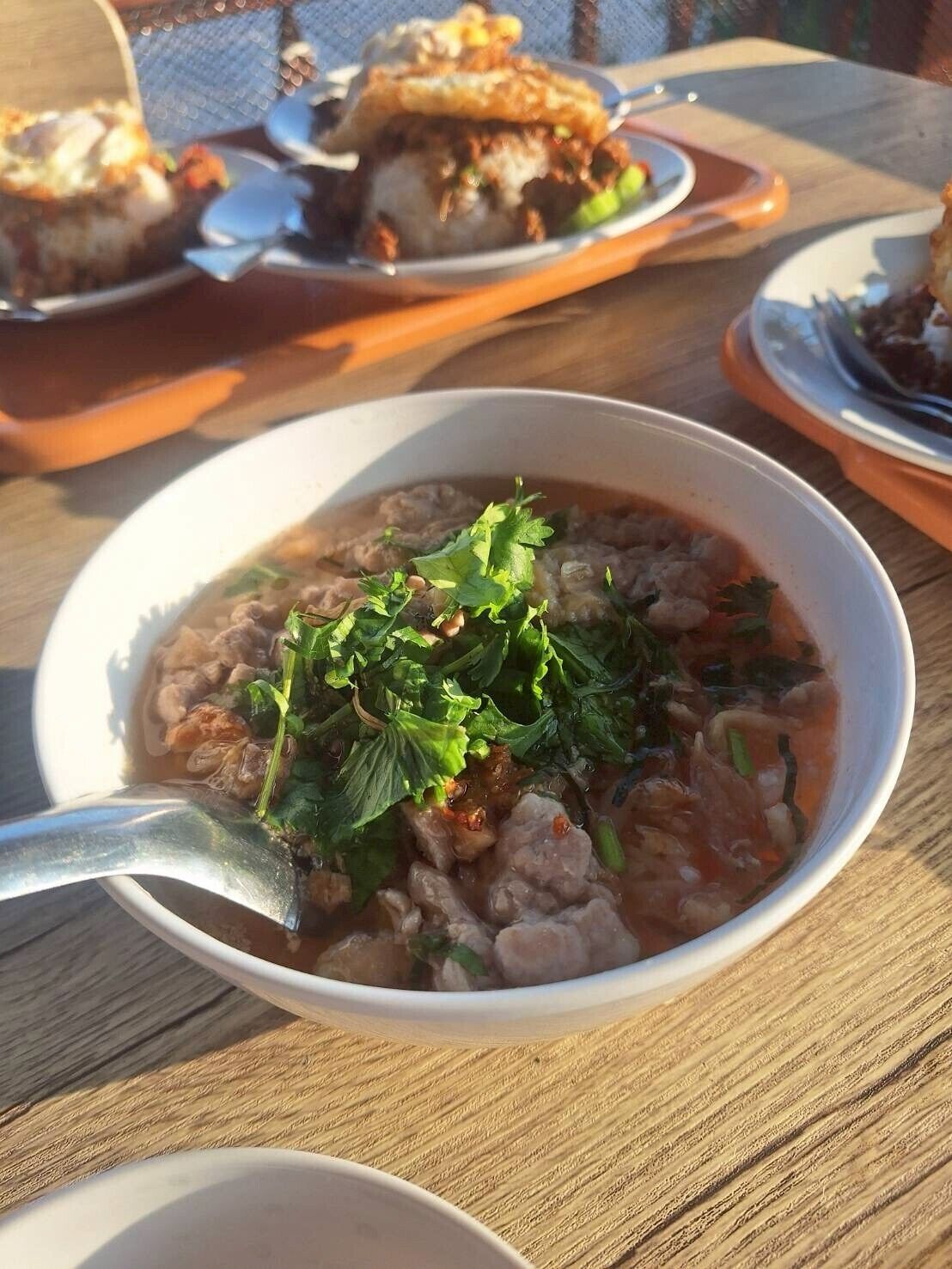 A bowl of soup garnished with herbs, served on a wooden table.