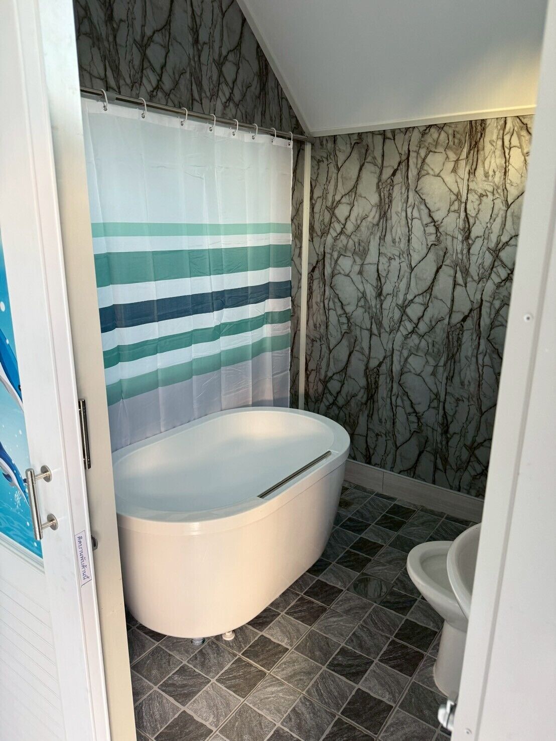 Ein Badezimmer mit Badewanne, Toilette und einer Duschvorhang mit horizontalen Streifen.