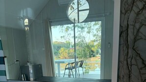 Een badkamer met een groot bad, een spiegel en uitzicht op een terras met stoelen.