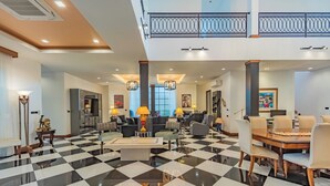 Un hall d’entrée spacieux, doté d’un sol à carreaux, de meubles modernes et d’un balcon agrémenté de balustrades décoratives.