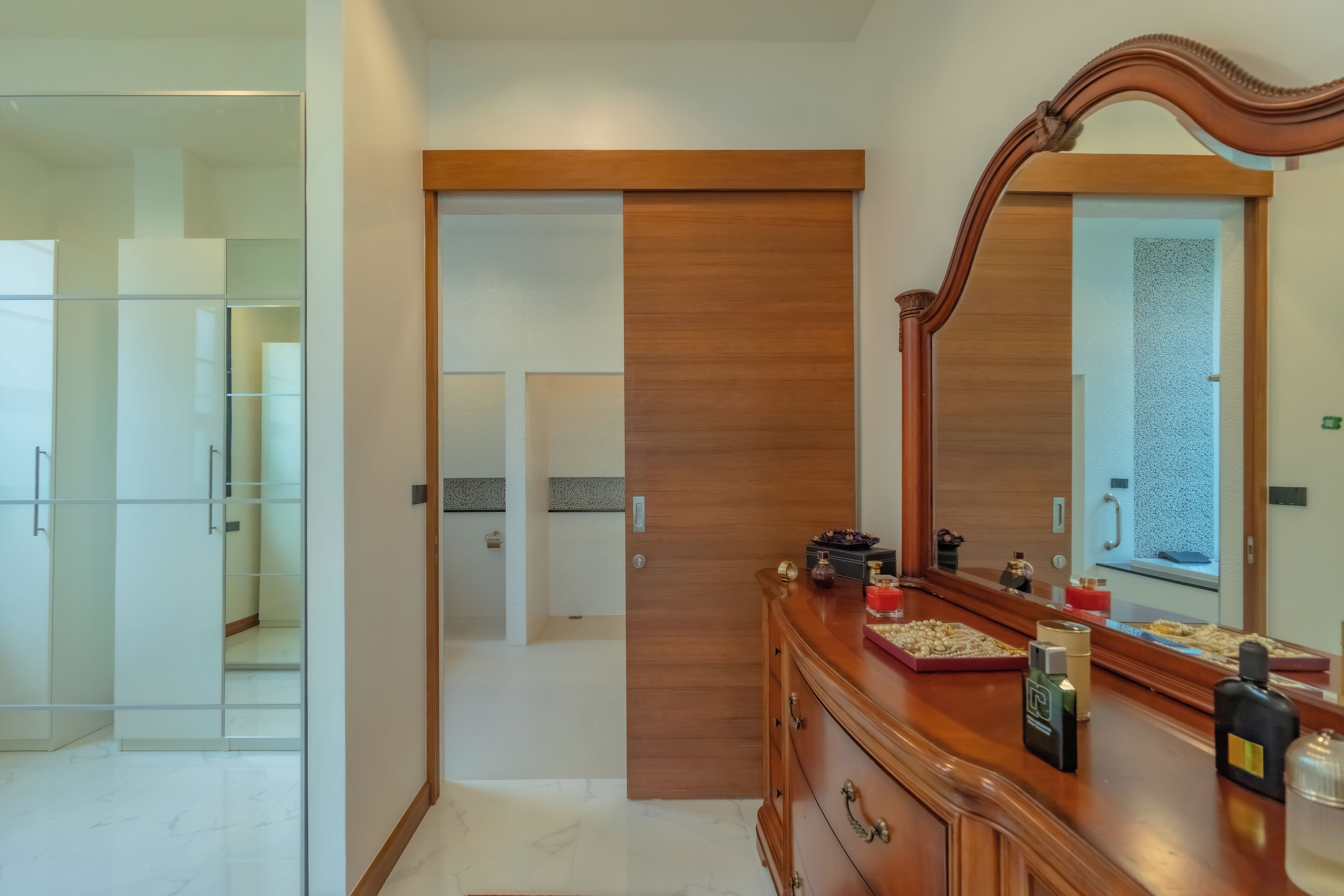 A modern bathroom with a wooden vanity, a large mirror, and a glass shower enclosure.
