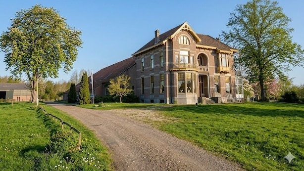 Un'ampia casa a due piani con un ingresso ben visibile, un vialetto e vegetazione circostante.