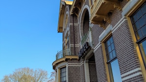 Un hotel storico con un ingresso ad angolo ben visibile, ampie finestre e un balcone con ringhiere elaborate.