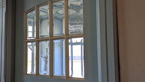 Una porta con un'ampia finestra, modanature decorative e un lampadario riflesso nel vetro.