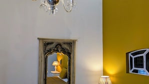 Una camera da letto con un letto, un lampadario, uno specchio, un comodino con una lampada e una finestra vista.