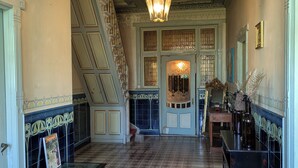 Un'imponente sala con un lampadario, una scala e vista su una stanza con un'ampia finestra.