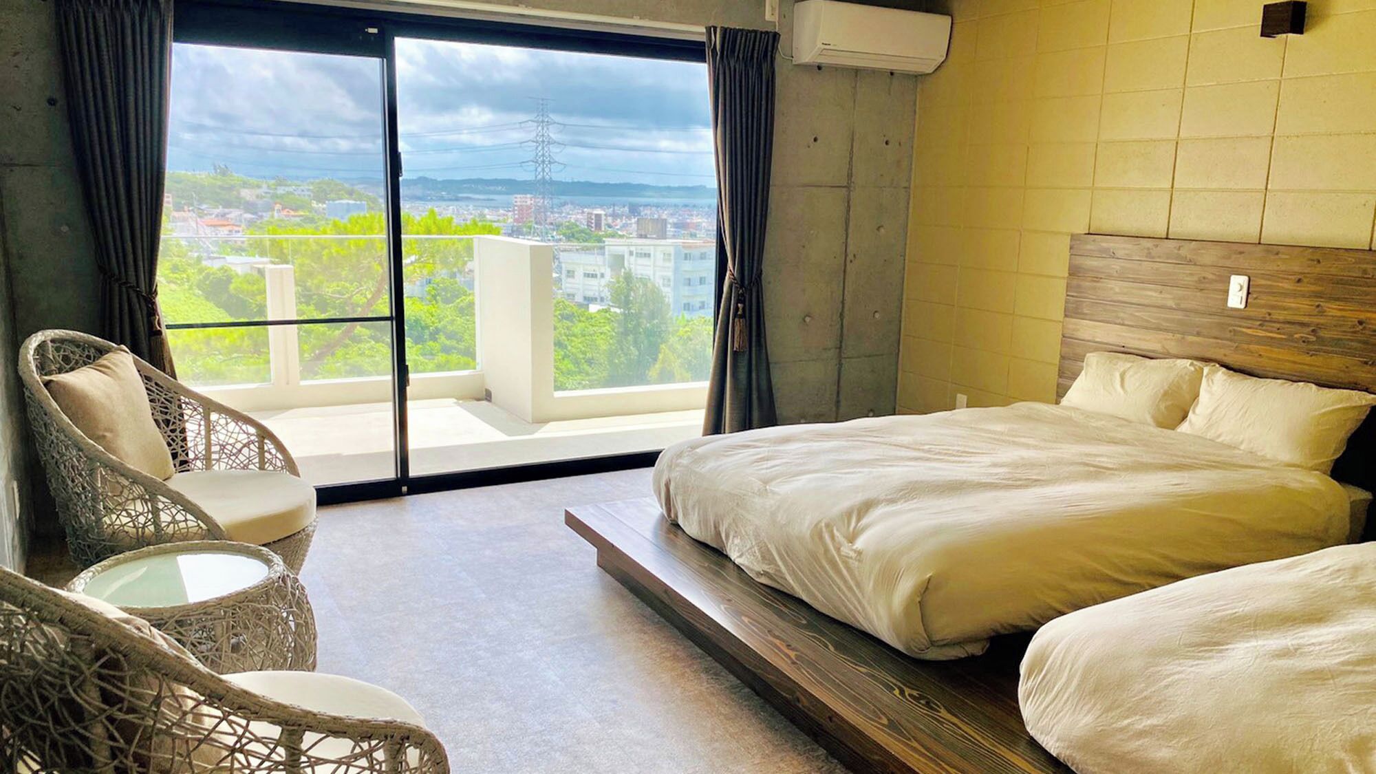 A hotel room with a bed, a chair, and a view of the city.