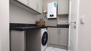 Ein kleiner Hauswirtschaftsraum mit Waschmaschine, Trockner und Warmwasserbereiter.