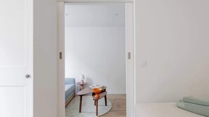 Ein Zimmer mit einem Bett, einem kleinen Tisch mit einer Schale, einer Lampe und einem Sofa.
