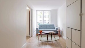 Ein modernes Wohnzimmer mit einem blauen Sofa, einem runden Couchtisch und einem kleinen Beistelltisch.