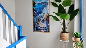 Käytävä, jossa on portaikko, kehystetty maalaus, jossa on kuvattuna merimaisema, ja ruukkukasveja.