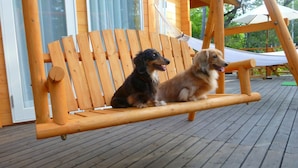 Two dogs sitting on a wooden swing bench outdoors. - Heart Land Hills In Noto 37 Trailer House Sho (Nanao)