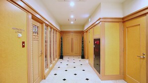 Un couloir d’hôtel avec des portes en bois, un sol carrelé et un sapin de Noël.