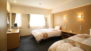 Une chambre d’hôtel avec deux lits, un bureau avec un ordinateur et un grand miroir.