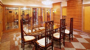 Un espace repas avec une table à plateau en verre, entourée de chaises en bois dotées d’assises rembourrées.