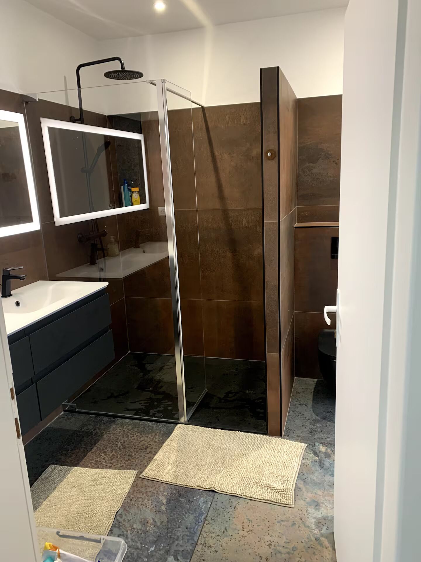 Un bagno moderno con box doccia in vetro, lavandino bianco e uno specchio grande.