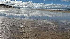 Una platja amb cel blau i aigua tranquil·la que reflecteix els núvols.