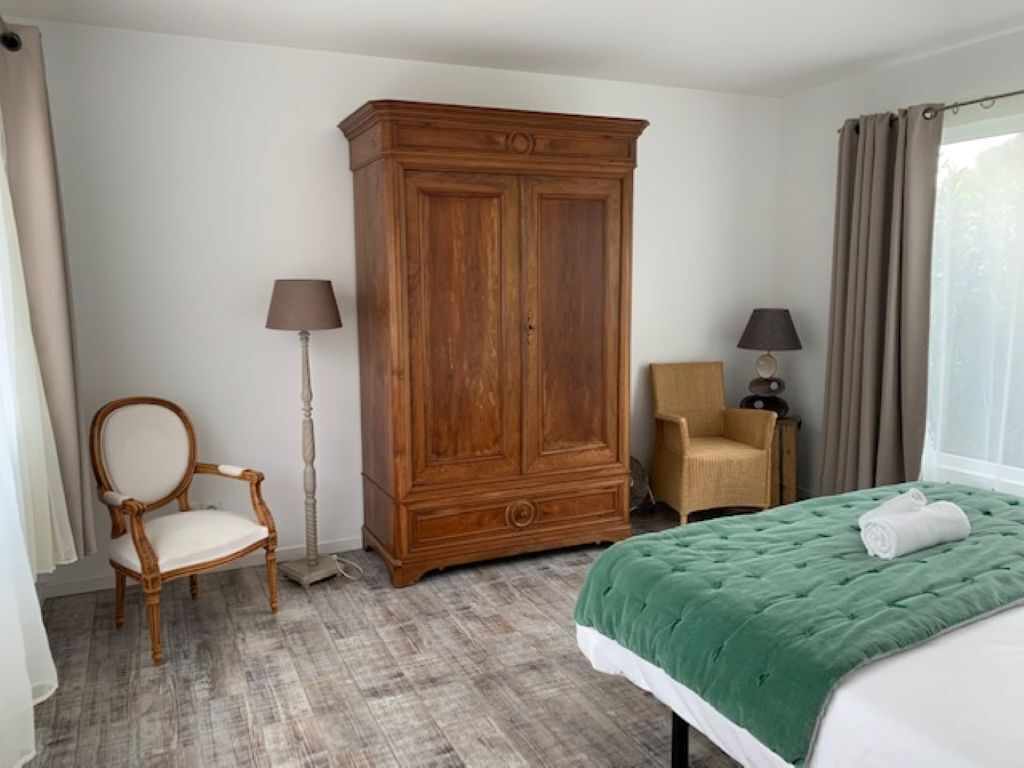 Une chambre à coucher comprenant un lit, une armoire en bois, une chaise et deux lampadaires.