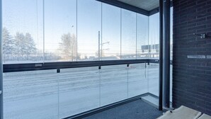 Ein verglaster Balkon mit Blick auf eine schneebedeckte Straße und Bäume.