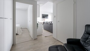 Eine moderne, minimalistisch eingerichtete Wohnung mit Wohnbereich, Küche und Schlafzimmer.
