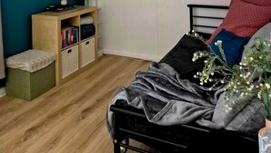 A bedroom with a bed, a bookshelf, a TV, and an air conditioning unit.