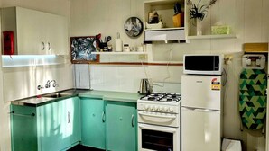 A compact kitchen with teal cabinets, a white stove, and a microwave.