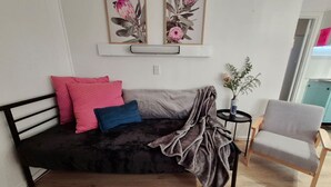 A cozy living room with a dark-colored sofa, a grey armchair, and two framed floral artworks on the wall.