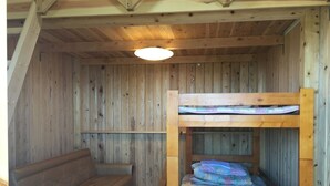 Interior de una cabaña de madera con literas y un sofá.