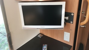 A white Panasonic TV mounted on a wall with a wooden cabinet above it. - Heart Land Hills in Noto 38 Trailer House Chu (Nanao)