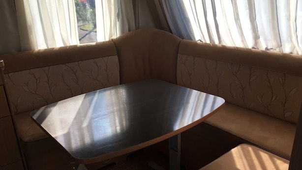 A compact, modern RV interior with a metallic table and cushioned seating. - Heart Land Hills in Noto 38 Trailer House Chu (Nanao)