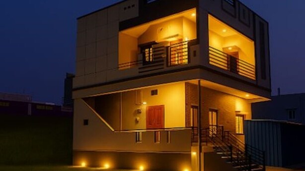 Een modern gebouw met twee verdiepingen, voorzien van een balkon op de bovenverdieping, een overdekte ingang en een trap naar de bovenverdieping.