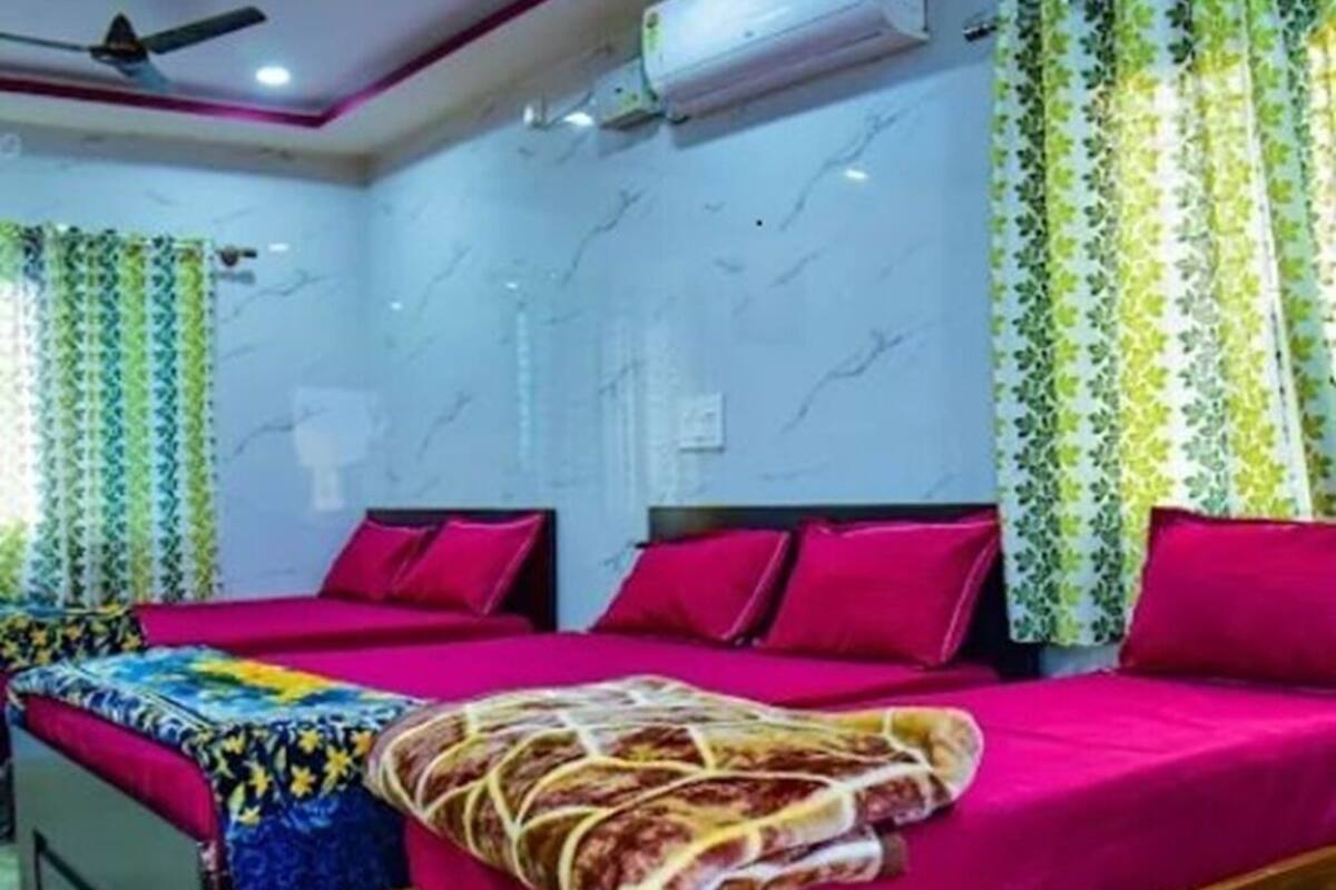 Une chambre d’hôtel avec deux lits, un ventilateur de plafond, un appareil de climatisation et des rideaux à motifs.