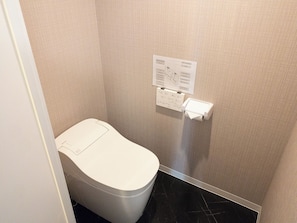 A small, modern bathroom with a toilet, a paper towel dispenser, and a wall-mounted instruction manual. - 602-Black Cool Room｜8 ppl | Custom Queen Bunk Beds｜Golden Gai & Kabukicho|42㎡ (Kabukicho,Shinjuku-ku)
