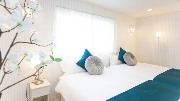 Een hotelkamer met een bed, nachtkastje, lamp en een raam met gordijnen.