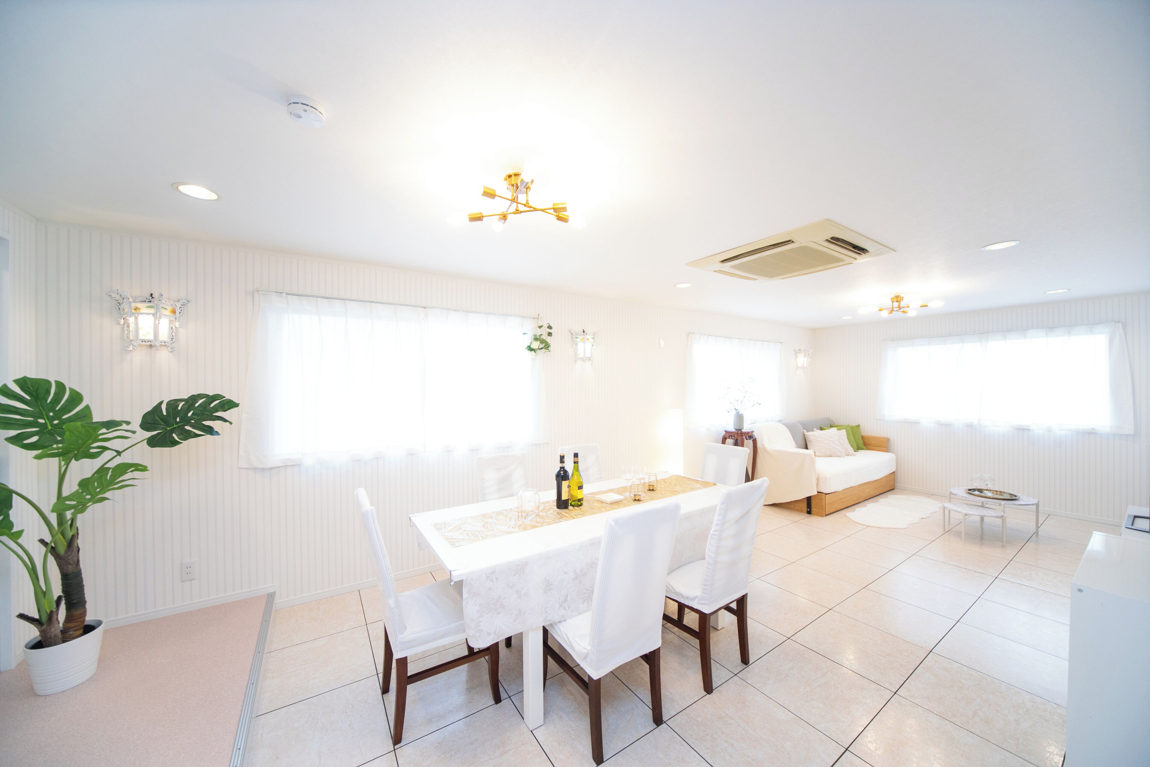 A bright, modern dining area with a white table, chairs, and a chandelier.