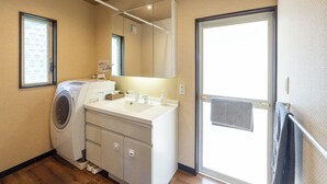 Un baño pequeño con lavadora, lavamanos y espejo.