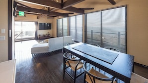 Un interior moderno con comedor, sofá y ventanas grandes con persianas.