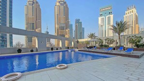Un área de piscina en la azotea con vistas a altos edificios al fondo.