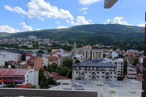 A cityscape with buildings, a prominent tower, and a hill in the background. - Skopje City Apartment 1 (Skopje)