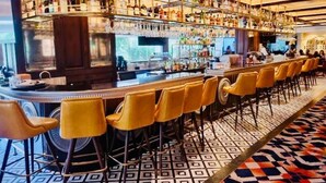A bar area with multiple shelves of bottles, a bar counter, and yellow bar stools. - Luxury Sea View 3 Bedroom AC Apartment 5 star hotel access and all amenities (Colombo)
